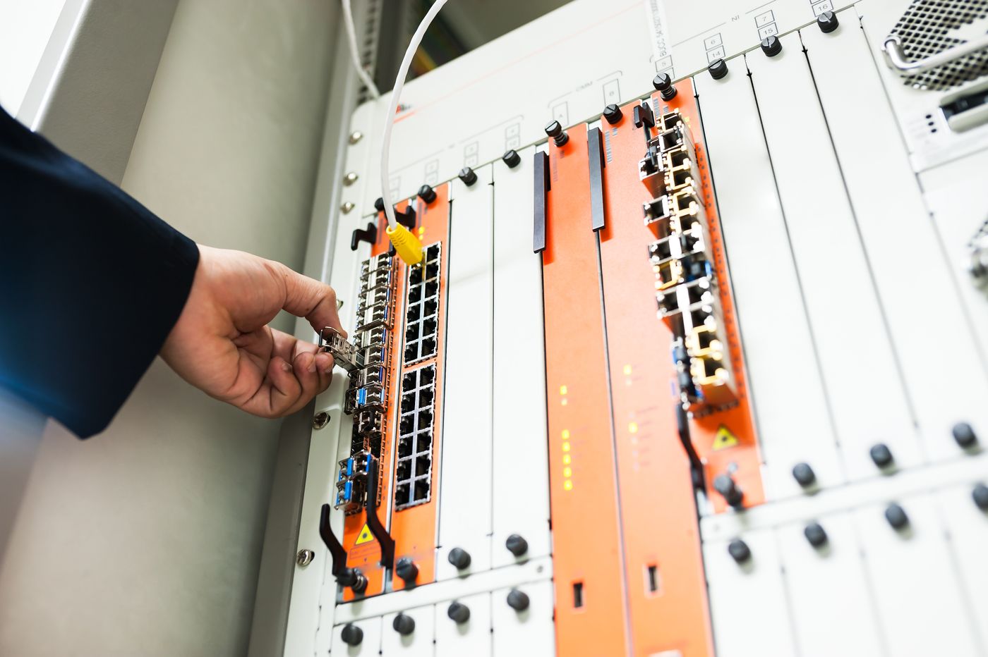 Technicien raccordant un module optique dans un châssis télécom